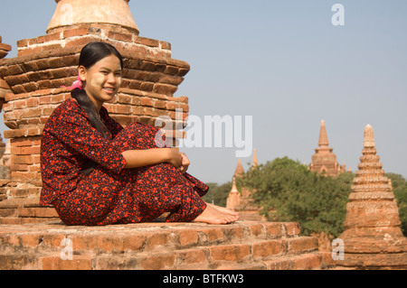 Jeune femme birmane dans une robe rouge assis sur le toit d'un temple , Bagan (Pagan), le Myanmar (Birmanie) Banque D'Images