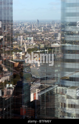 Réflexions de Londres et à Canary Wharf bâtiments comme vu dans et par une fenêtre dans un grand immeuble de bureaux Banque D'Images