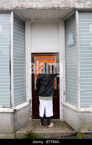 Une femme essaie de voir derrière un aveugle d'un magasin vide à Falmouth, Royaume-Uni Banque D'Images