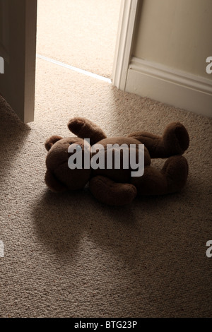 Ours en peluche de l'enfant allongé sur le sol d'une chambre avec une porte ouverte Banque D'Images