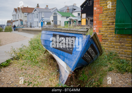 Un bateau à rames en bois la publicité Whitstable Oyster Company sur la plage sur Whitstable Banque D'Images