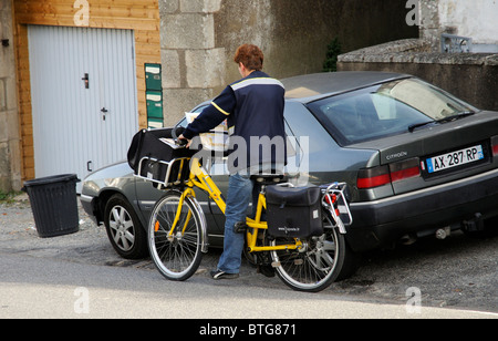 Équitation française factrice sa bicyclette peint jaune dans la ville rurale d'Aizenay Vendée de France Banque D'Images