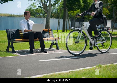 Businesswoman on bike passant un businessman outdoors Banque D'Images