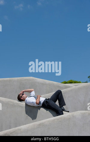 Homme avec cravate et lunettes de soleil couché sur le mur Banque D'Images