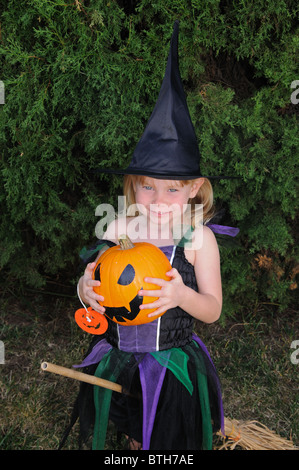 Jeune Fille habillée comme une sorcière (tenant une citrouille) pour l'Halloween, Mijas Costa, Costa del Sol, la province de Malaga, Andalousie, espagne. Banque D'Images