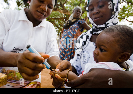 Un agent de santé marque le doigt d'un enfant avec de l'encre au cours d'un exercice national de l'immunisation contre la polio Banque D'Images