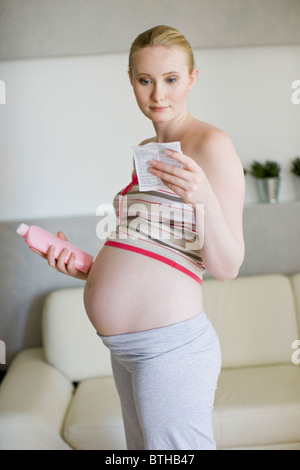 Femme enceinte l'enseignement de la lecture pour lotion Banque D'Images