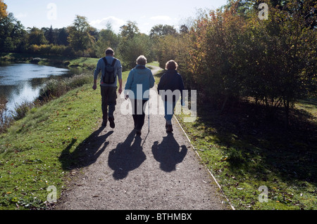 Trois promeneurs marchant sur un sentier sur les rives de la rivière du Jubilé au lac fin près de Dorney Berkshire UK Banque D'Images