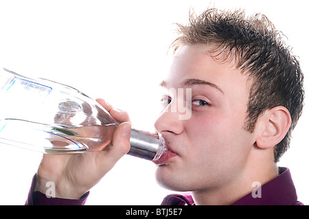 Le jeune homme boit une bouteille de vodka. Isolé Banque D'Images