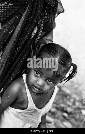 Pauvre petite fille indienne avec la mère dans la rue en Inde. Noir et blanc avec une mise au point sélective. Banque D'Images