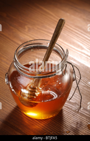 Pot de miel et bâton en bois. Les objets sont sur la table en bois. Banque D'Images
