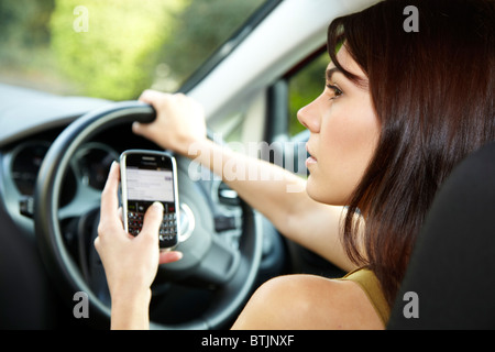 Femme au volant et à l'aide de mobile phone Banque D'Images