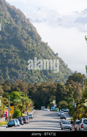 Franz Josef,Ville,pics enneigés des Alpes du Sud, au prorata des arbres dans le parc national de Westland,Fleurs,Îles du Sud, Nouvelle-Zélande Banque D'Images