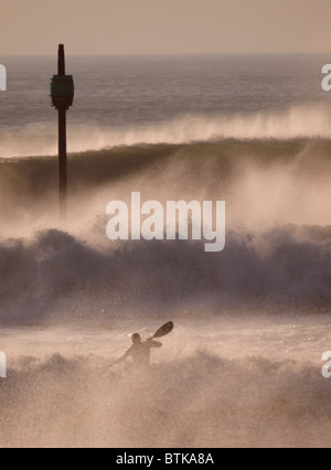 Kayakiste de surf dans d'énormes vagues de tempête, Bude, Cornwall, UK Banque D'Images