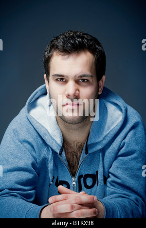 Portrait d'un jeune homme dur avec les cheveux foncés - isolé sur le bleu foncé Banque D'Images