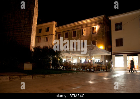 Scène de rue dans la vieille ville de Porec en soirée avec des réflexions sur les dalles et les images floues de personnes à pied Banque D'Images