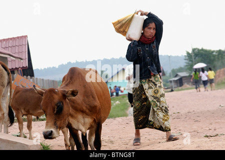 Une femme est porteur d'une grande bouteille d'eau potable sur son épaule près du principal marché de Muang Sing, le Laos. Banque D'Images