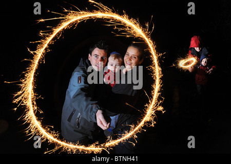 Feux d'artifice en famille Jeune couple et enfant avec un petit peu de sparkler feu de joie nuit Banque D'Images