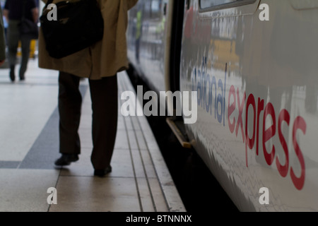 Les navetteurs passant devant le train National Express sur le quai de la gare de Liverpool Street, Londres, Royaume-Uni Banque D'Images