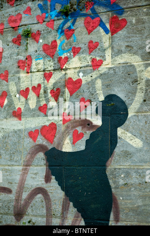 Le Graffiti montrant une jeune fille en noir coeur rouge laissant échapper / fly à partir de son tablier, mur à Munich, Allemagne Banque D'Images