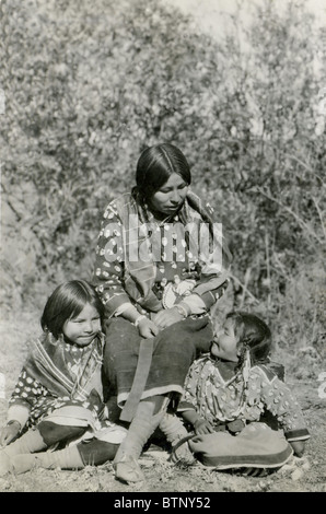 Une photo montrant un Native American Indian mère dire à ses deux filles histoire vêtus de vêtements autochtones. Cette photo est en noir et blanc. Banque D'Images