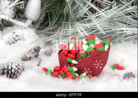 Portrait d'un traîneau de Noël rempli de maïs bonbons colorés maison de vacances situé dans un arbre de pin, de neige fond. Banque D'Images