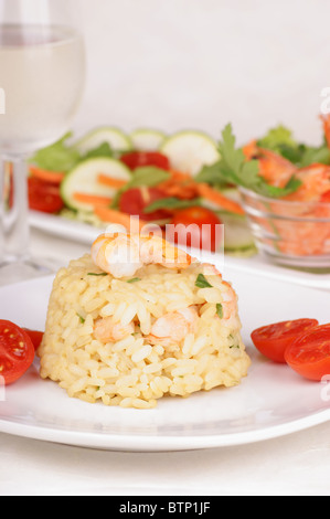 Risotto aux crevettes servi sur une plaque blanche et décoré avec des tomates cerises. Banque D'Images