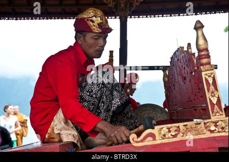 Le gamelan balinais musiciens jouant de leurs instruments à Bali portant un costume traditionnel avec des couleurs rouge vif Banque D'Images