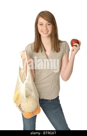 Jeune femme avec string réutilisable écologique panier rempli de fruits frais, tenant une pomme. Banque D'Images