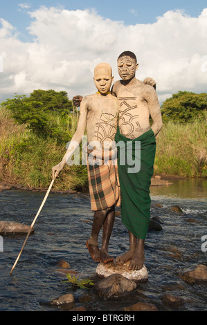 Surma man and boy avec peintures corps debout dans la rivière, la vallée de la rivière Omo, Kibish, Ethiopie Banque D'Images