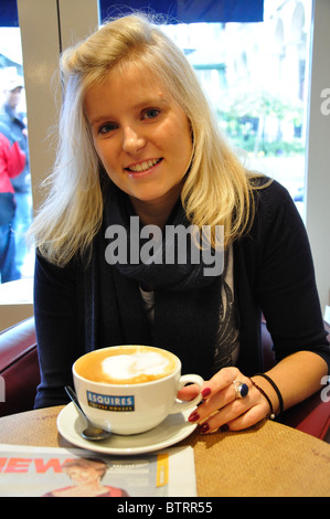 Jeune femme ayant cappuccino au café de l'Esquire, High Street, Windsor, Berkshire, Angleterre, Royaume-Uni Banque D'Images