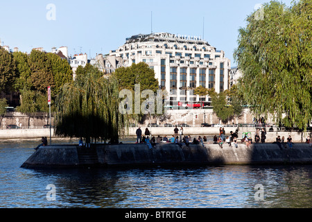 Les eaux bleues de Seine séparer autour de la pointe de l'Ile de la cité où les parisiens le long du bord du quai bénéficiant d'automne chaud soleil Banque D'Images