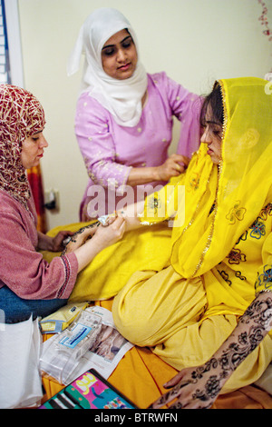 Jeune musulman bride-à-être a élaborer des dessins au henné peints sur ses bras et ses mains par sa fille musulmane ami avant son mariage Banque D'Images