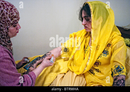 Jeune musulman bride-à-être a élaborer des dessins au henné peints sur ses bras et ses mains par sa fille musulmane ami avant son mariage Banque D'Images