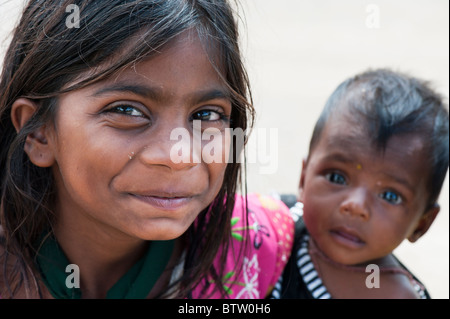 Pauvre fille indienne avec un sourire heureux tenant sa petite sœur. L'Inde. Selective focus Banque D'Images