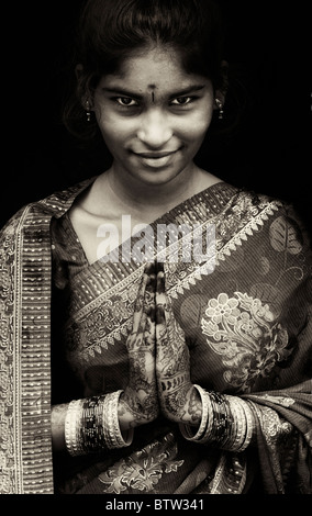 Indian girl smiling vêtu du costume traditionnel sari en soie de henné la prière les mains. L'Inde. Sépia Banque D'Images