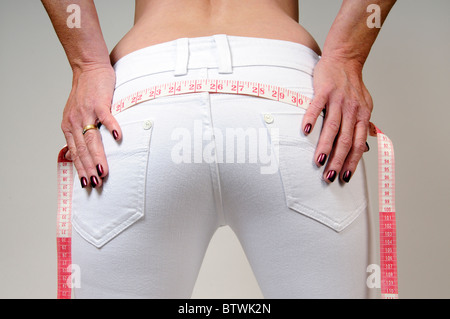 Woman's hands holding d'un ruban à mesurer à travers son dos Femme d'âge moyen de propagation Banque D'Images