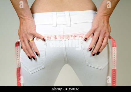 Woman's hands holding d'un ruban à mesurer à travers son dos Femme d'âge moyen de propagation Banque D'Images