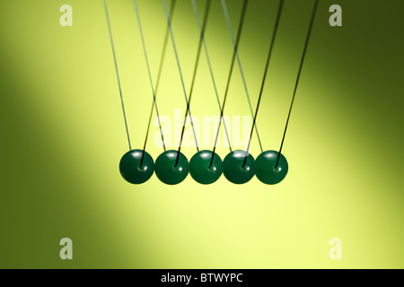 Cinq billes vertes dans la rangée suspendu à chaîne. Newton's cradle, illustre un appareil qui démontre la conservation de l'impulsion. Banque D'Images