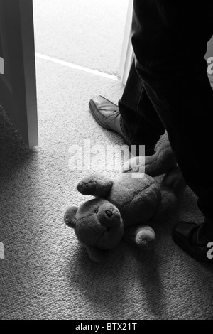 Les jambes de l'homme et pas un enfant feett passé l'ours sur le sol pour quitter la salle. Banque D'Images