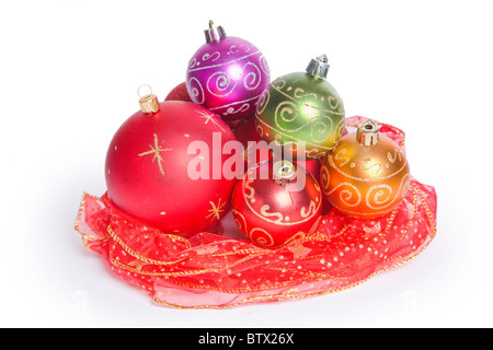 Boules de Noël niché dans un nid de ruban rouge avec un fond blanc. Studio isolé. Banque D'Images