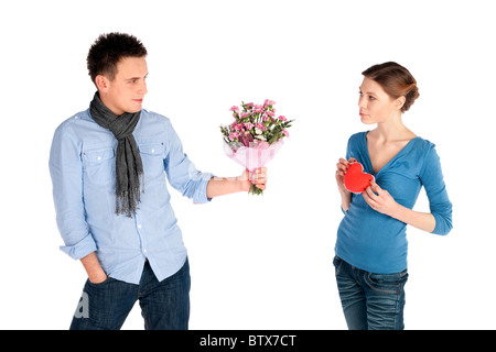 Jeune beau couple dans l'amour. Woman coeur, l'homme qui offre des fleurs, isolé sur fond blanc. Banque D'Images