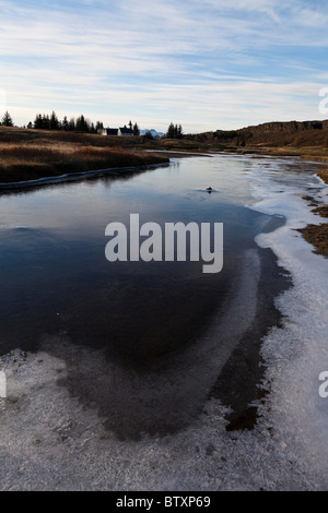 Rivière gelée semi-Oxara avec Thingvalla Kirkja église dans la distance, le Parc National de Thingvellir, Islande. Banque D'Images