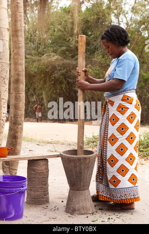 Une femme africaine à l'aide d'un grand mortier et pilon pour broyer les légumes Banque D'Images