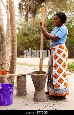 Une femme africaine à l'aide d'un grand mortier et pilon pour broyer les légumes Banque D'Images