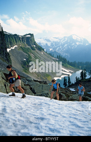 Trois randonneurs naviguer un névé sur la chaîne de lacs sentier près de Mt. Baker dans l'état de Washington. Banque D'Images