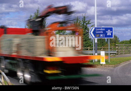 Articulted camion passant signe montrant début de l'autoroute M1 près de Leeds Yorkshire UK Banque D'Images