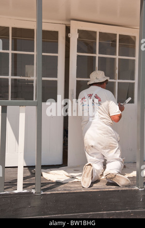 Un homme peint une cabane de plage sur le front de mer, à Southwold, Suffolk , Bretagne , France Banque D'Images