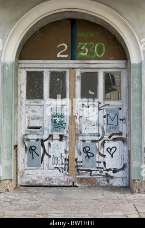 Différents types de graffitis / gribouillis sur une porte en bois dans une arche à Berlin, Allemagne Banque D'Images