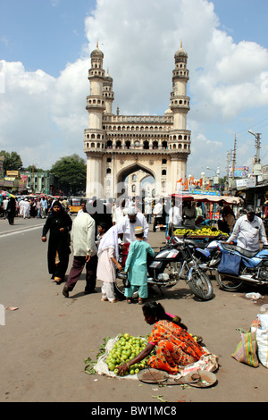 Scène de rue animée avec des personnes vendant des légumes et avec le Charminar en arrière-plan ; Hyderabad Inde Banque D'Images